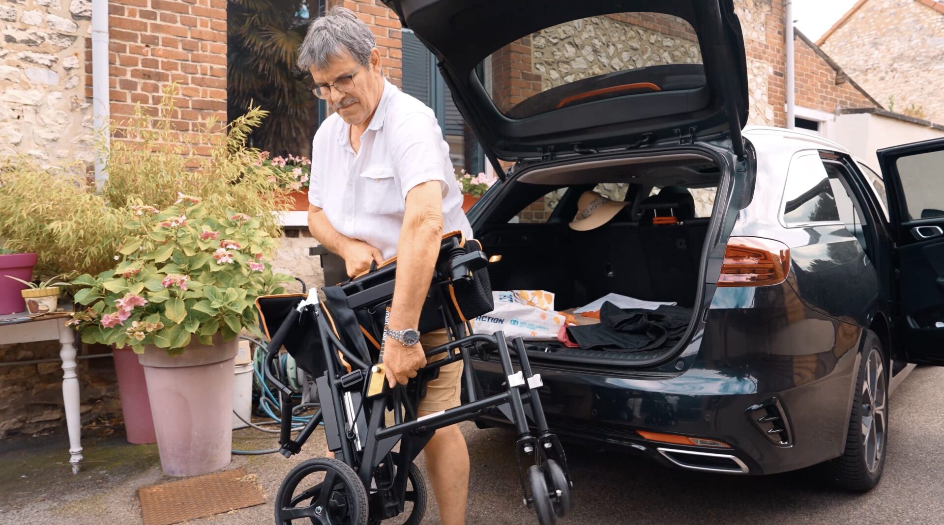 Un aidant charge le SmartChair Lite plié dans le coffre d'une berline sans effort — fauteuil roulant électrique ultra-léger Acekare