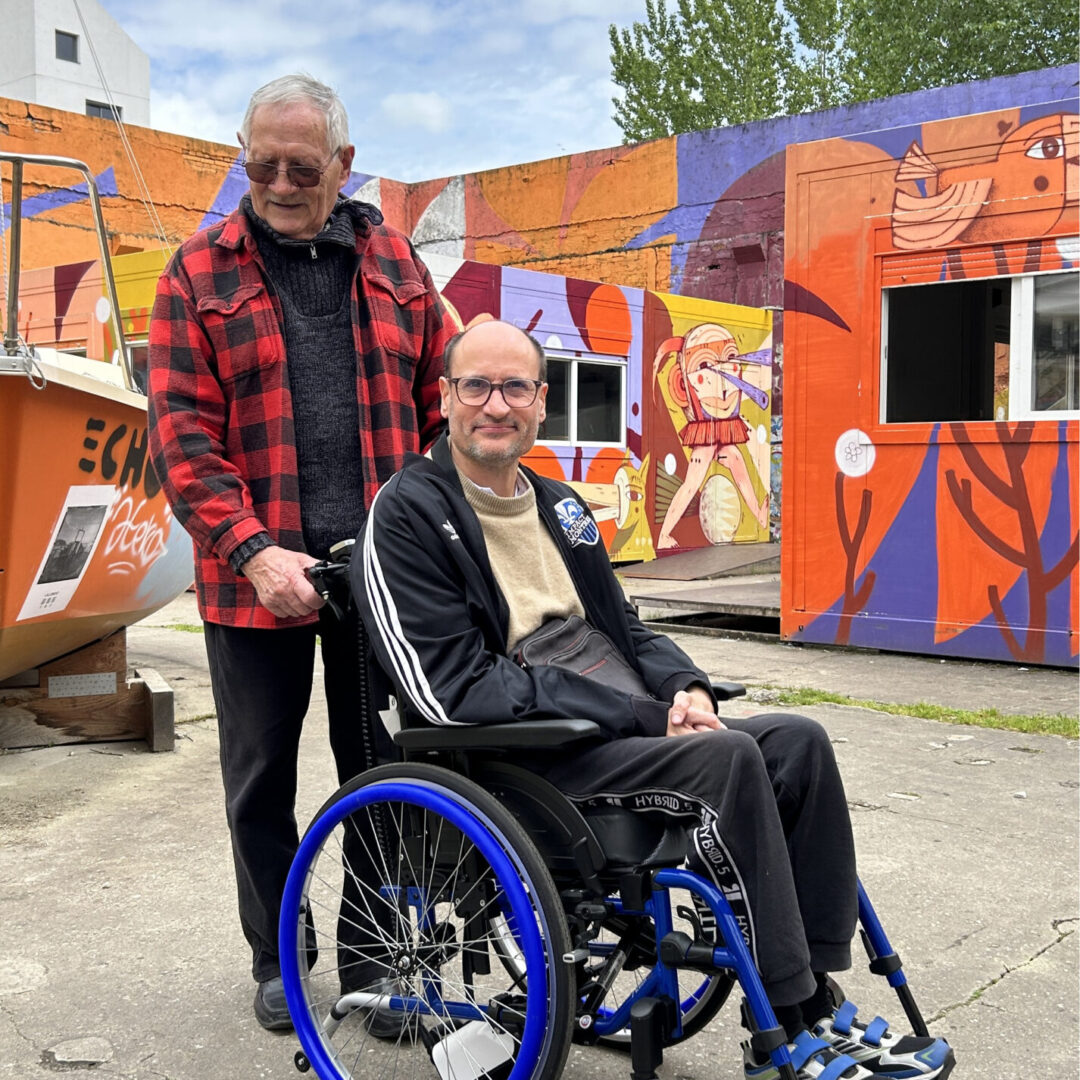 Daniel et Stéphane profitent d'une balade grâce à l'assistance Enjo, une motorisation pour fauteuil roulant manuel facilitant les déplacements et offrant une grande autonomie.